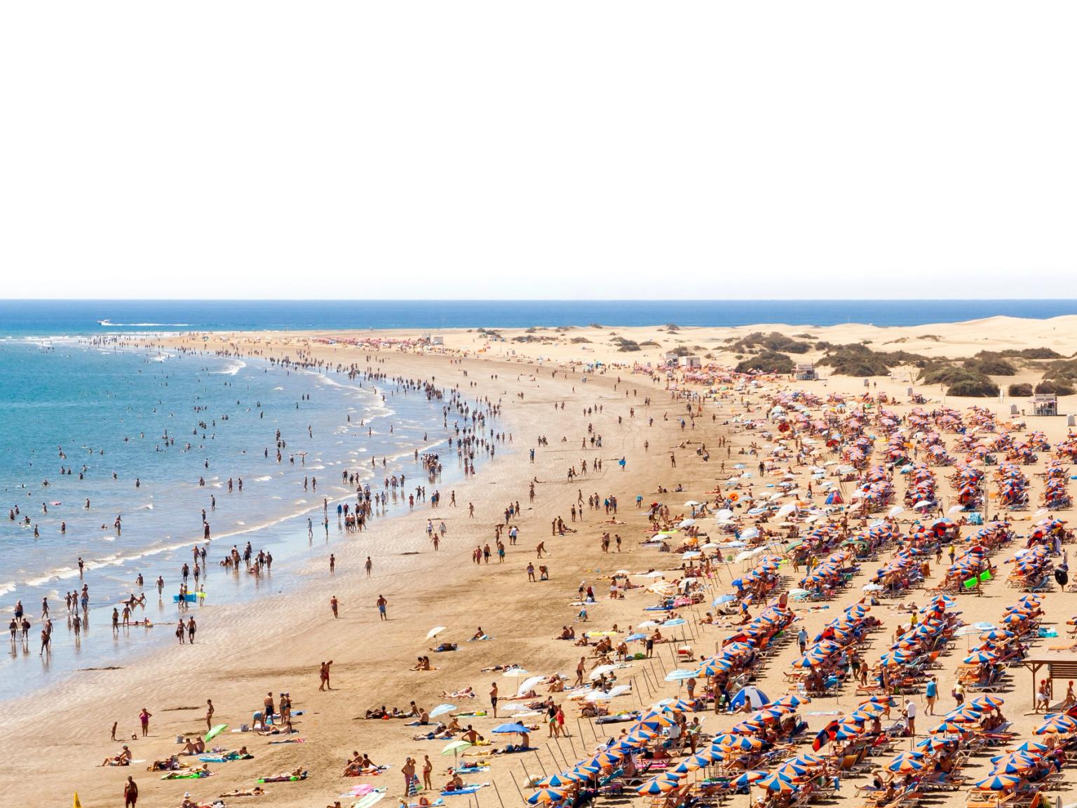 en meget overfyldt strand med masser af mennesker og paraplyer
