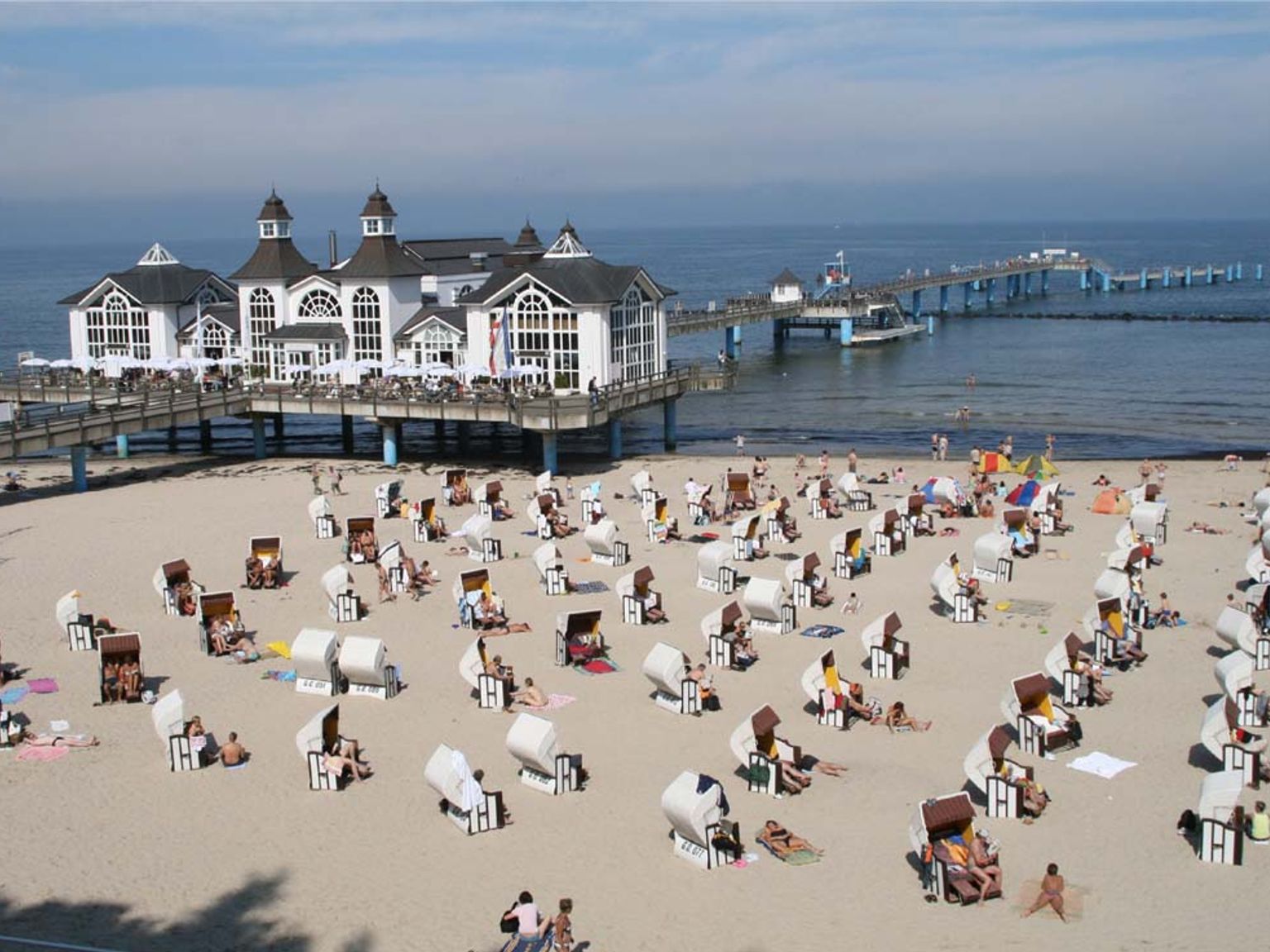 en strand fylt med mange stoler og mennesker på en solrik dag.