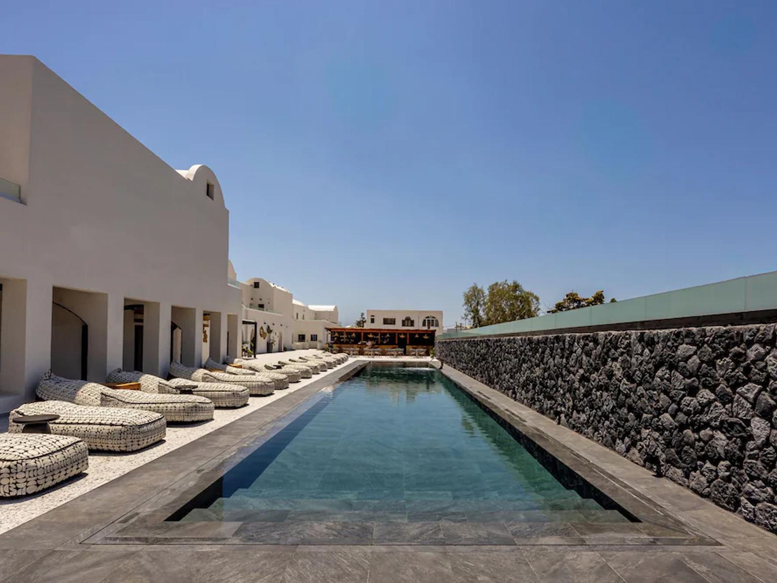 en stor swimmingpool omgivet af stole og en stenmur