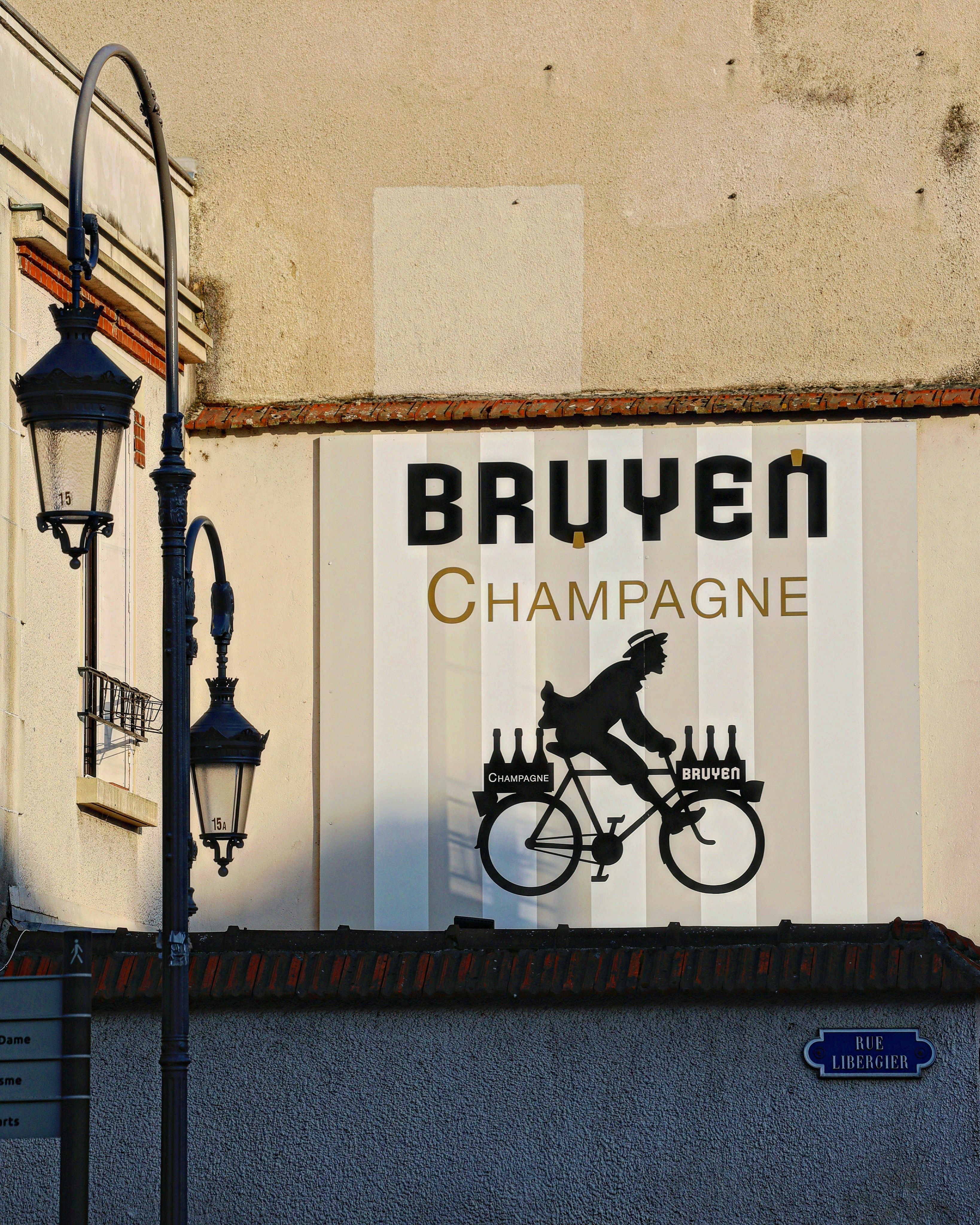 Mural para Bruyen Champagne que muestra a un ciclista con botellas junto a una farola.