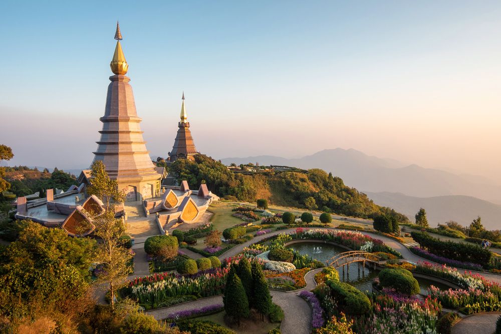 et tempel på toppen af en bakke omgivet af blomster og træer, Chiang Mai - Thailand