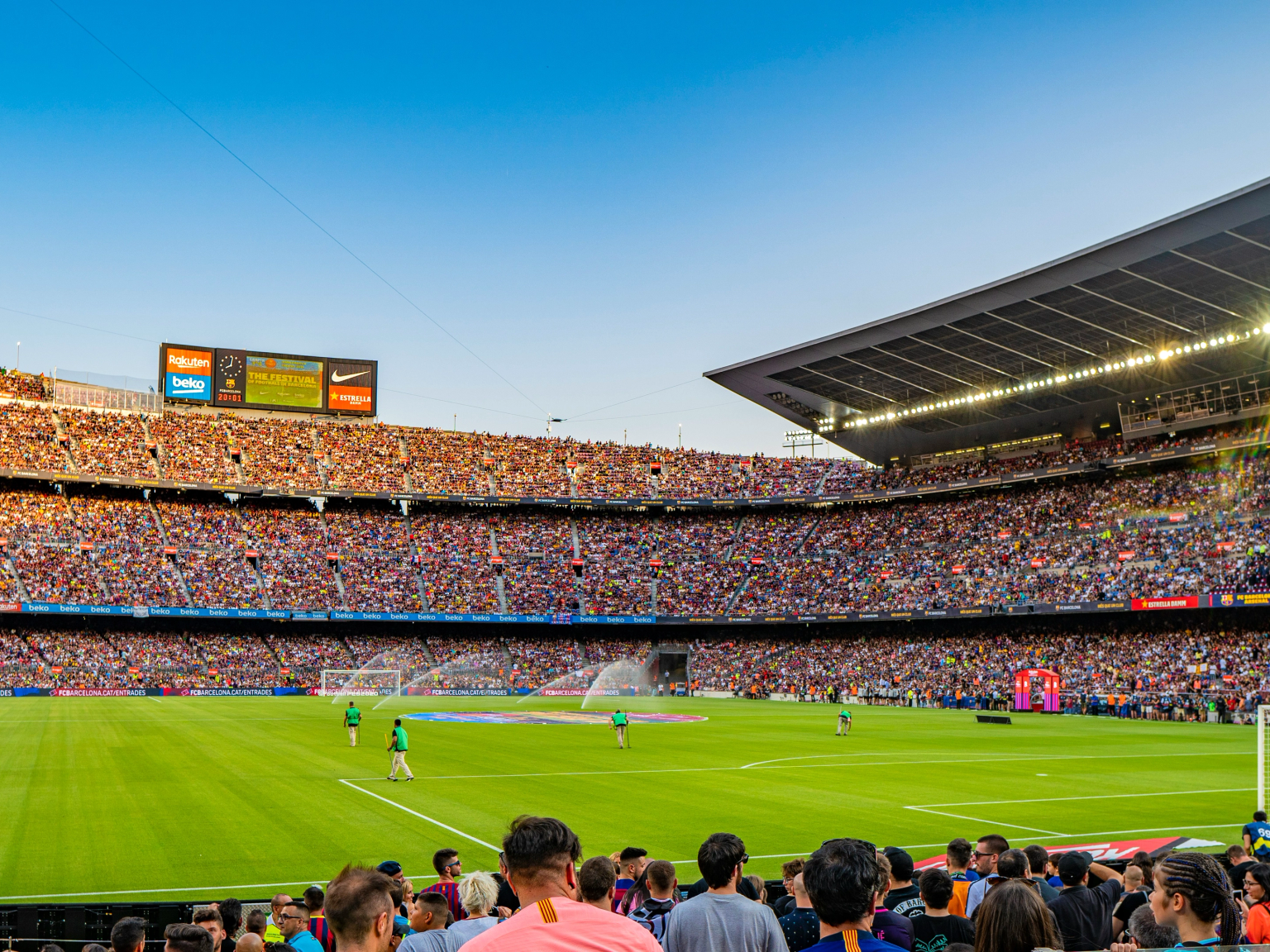 Vollbesetztes Fußballstadion mit Spielern auf dem Feld.