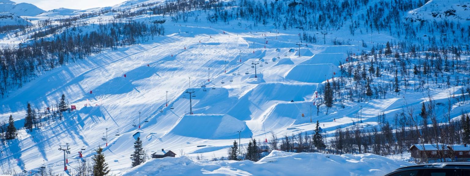 en bil er parkeret i sneen nær en skisportssted