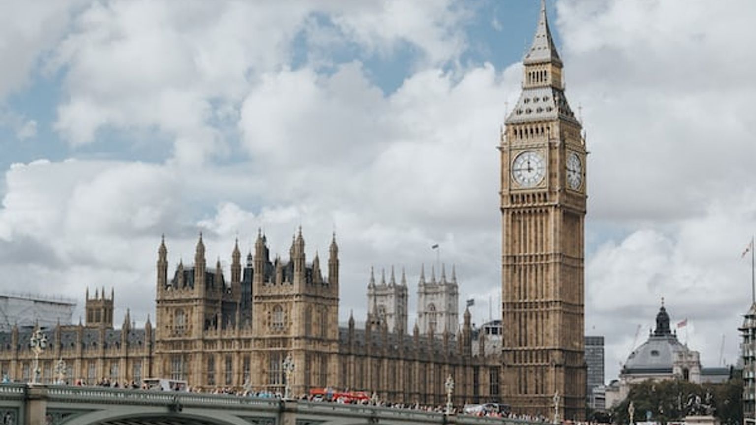Big Ben, a clock tower in London with a bridge in front of it.
