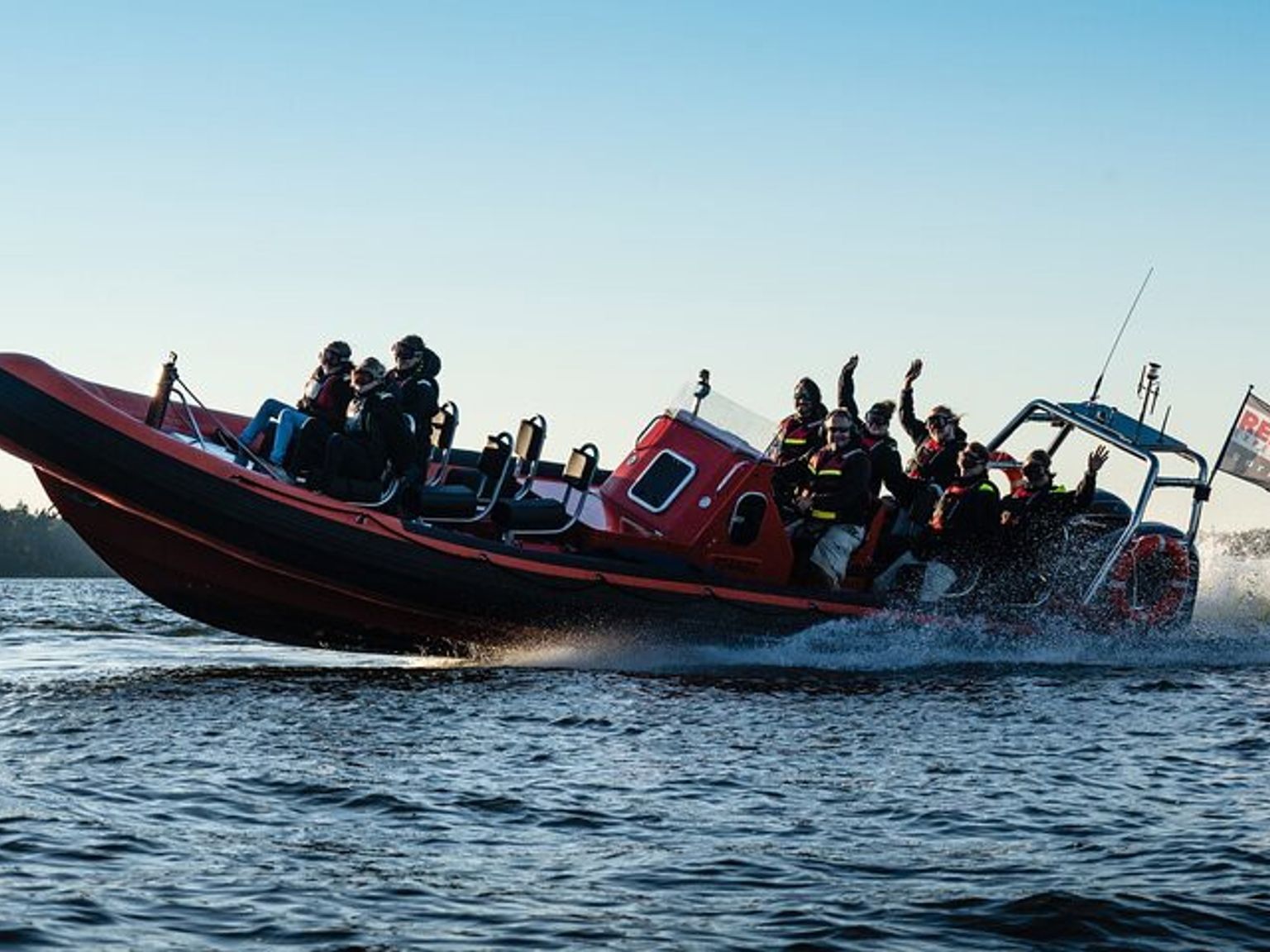 a group of people are riding in a red boat on a lake