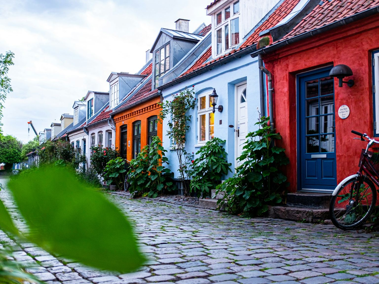en rad av färgglada hus på en kullerstensgata med en cykel parkerad framför ett av husen
