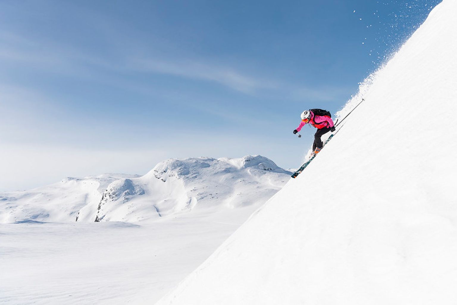 en kvinne står på ski nedover et snødekket fjell