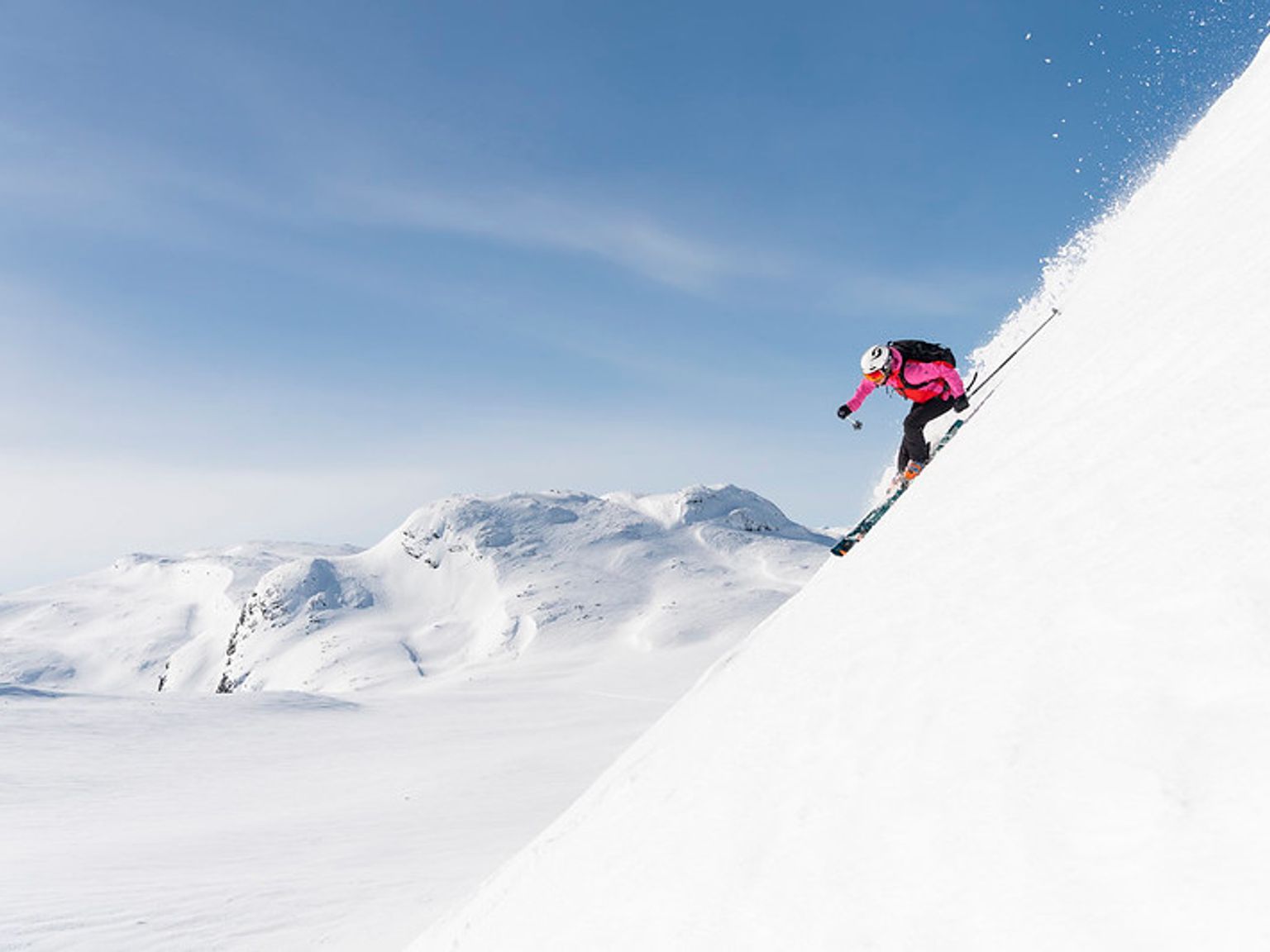 en kvinne står på ski nedover et snødekket fjell