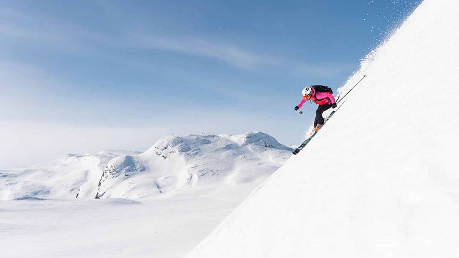 en kvinne står på ski nedover et snødekket fjell