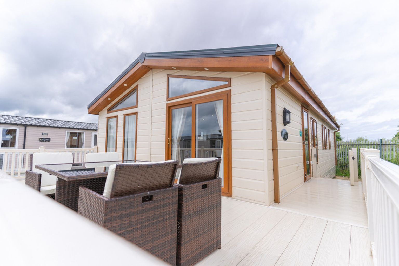 a mobile home with a deck and patio furniture in front of it