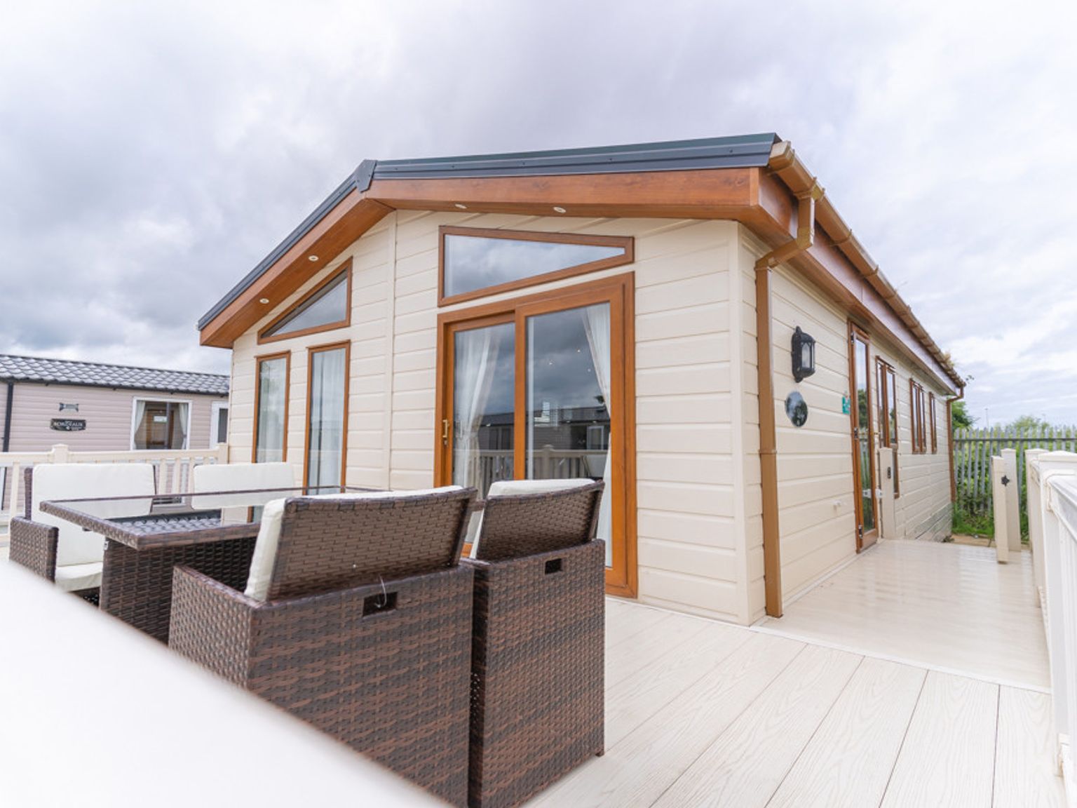 a mobile home with a deck and patio furniture in front of it