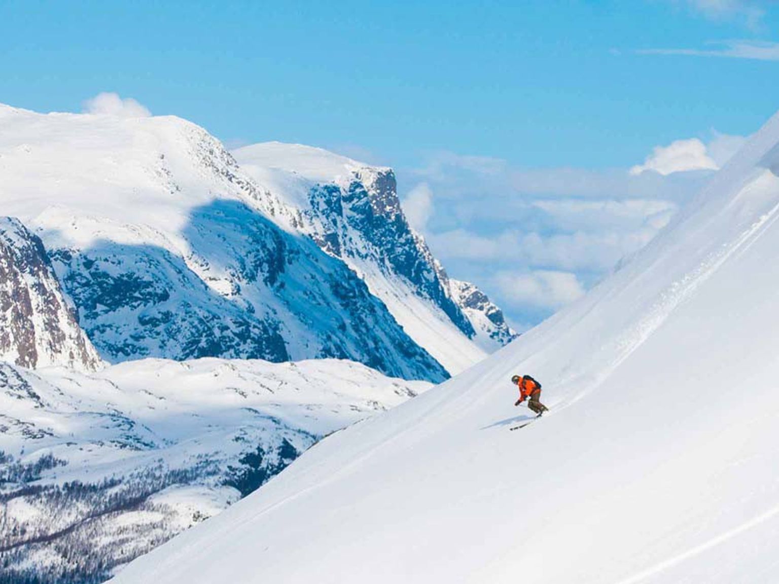 en person står på ski ned ad et sneklædt bjerg