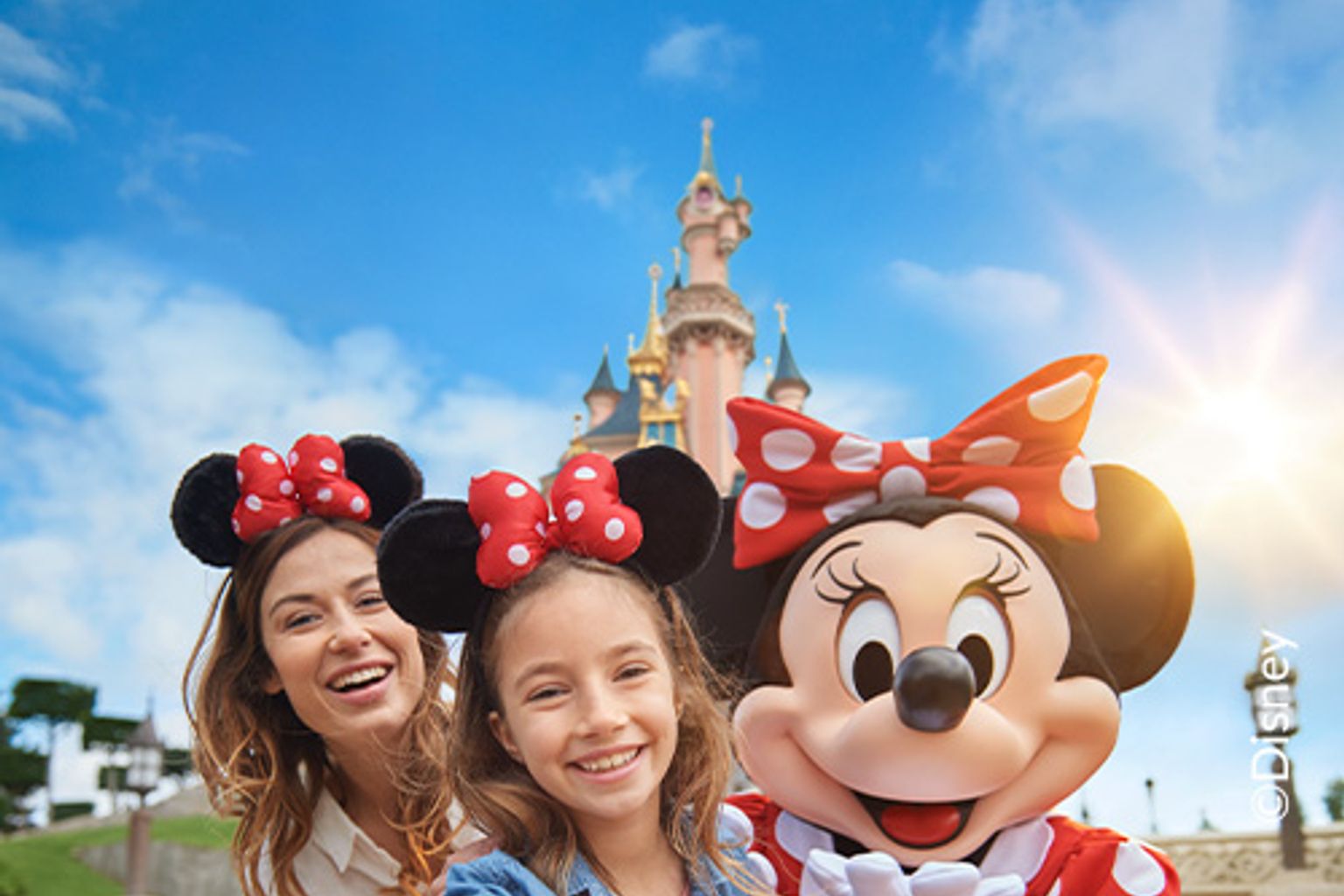 en kvinna och två barn tar en selfie med minnie mouse framför ett slott