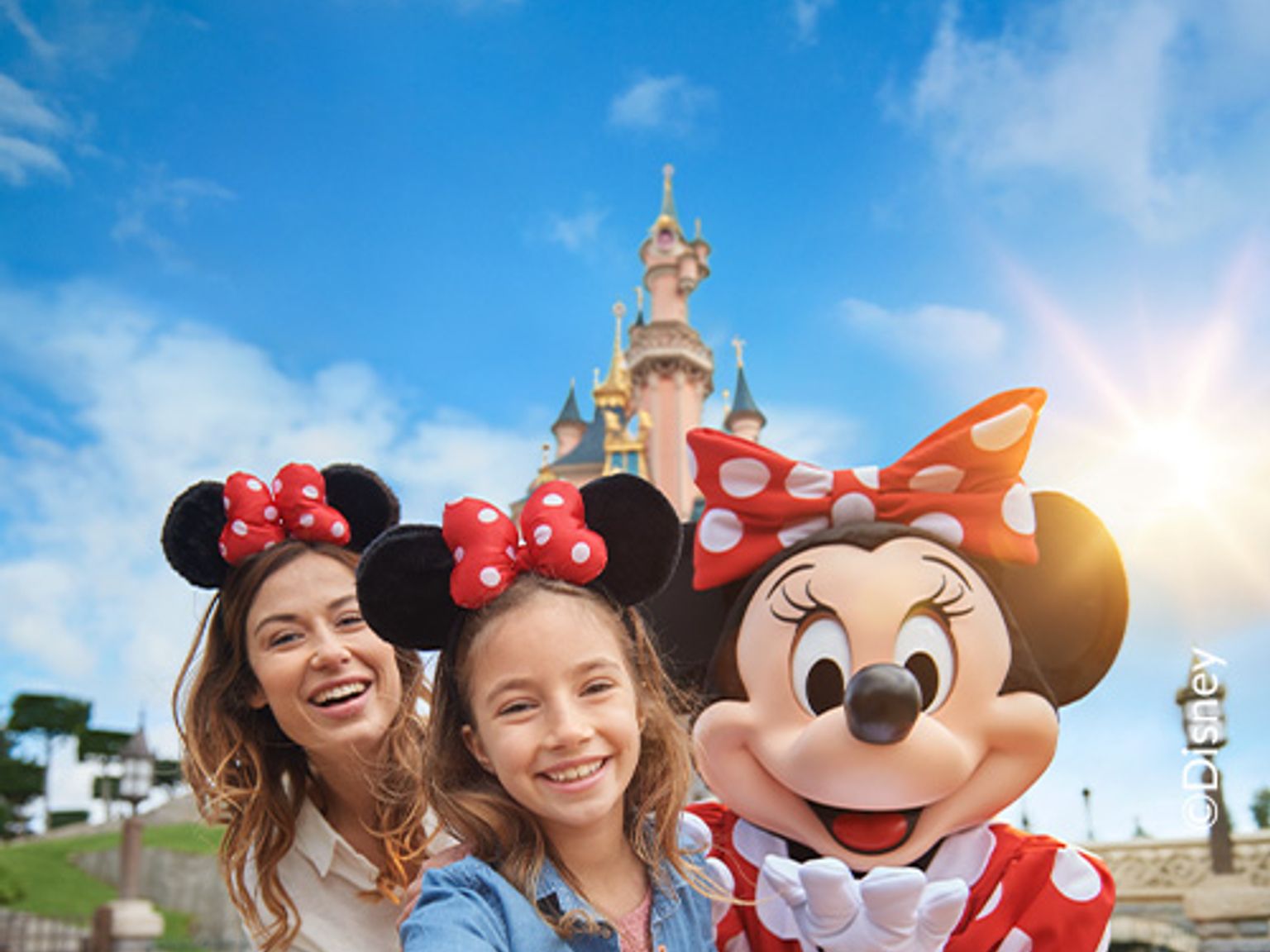 en kvinna och två barn tar en selfie med minnie mouse framför ett slott