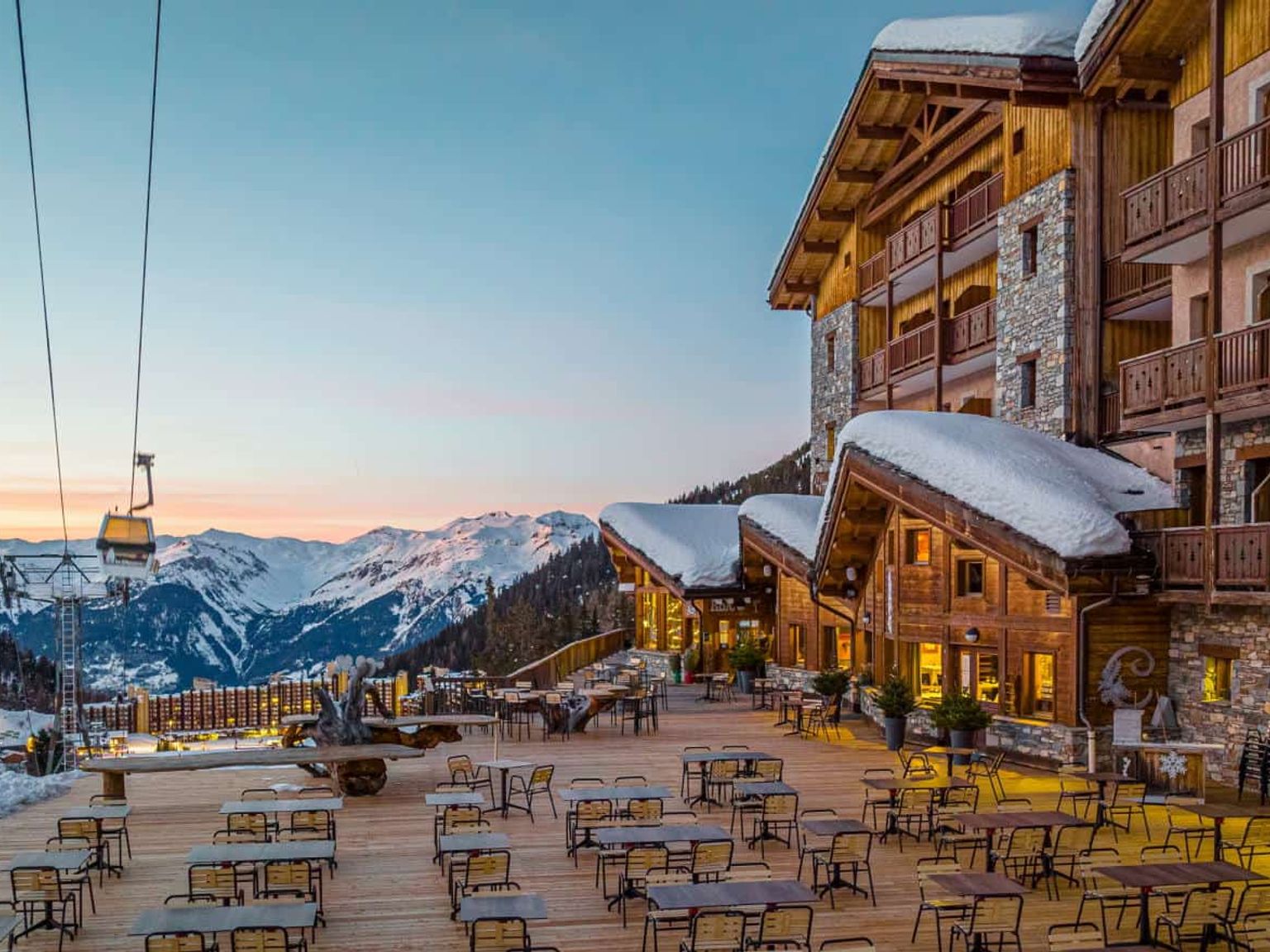 en stor byggnad med många bord och stolar framför, Hôtel Le Carlina av Les Etincelles, Les Arcs