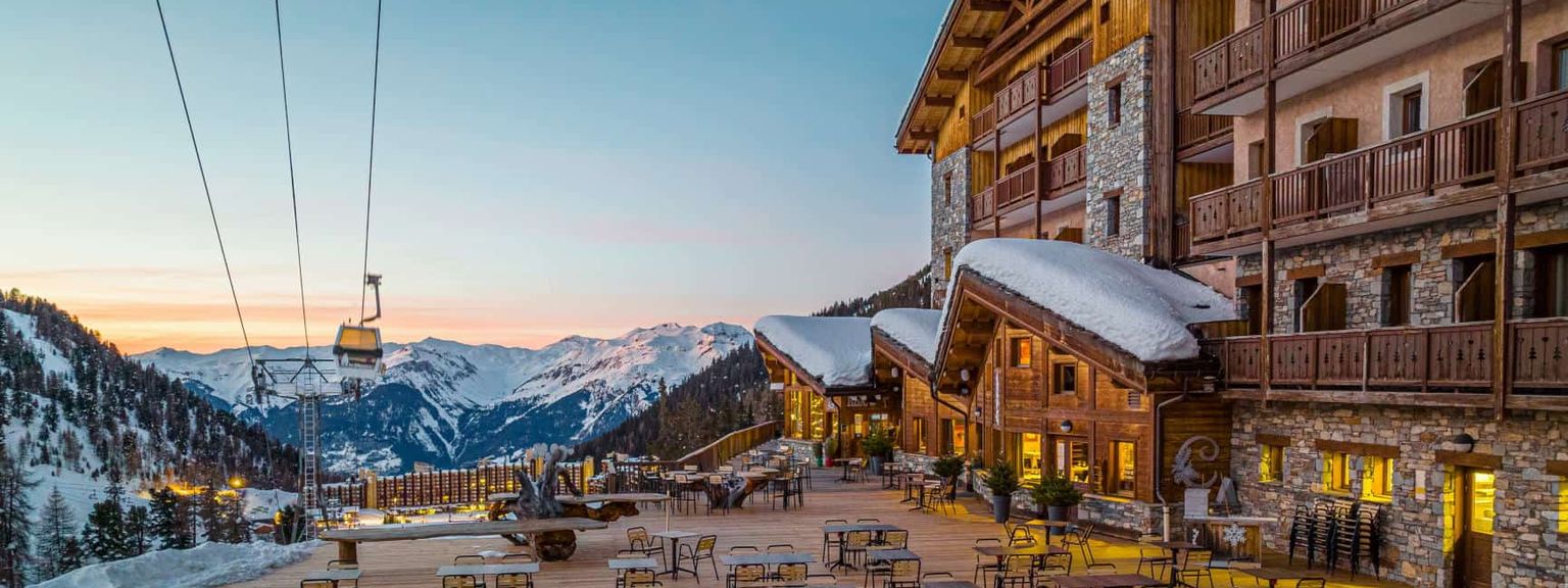 en stor bygning med mange bord og stoler foran, Hôtel Le Carlina av Les Etincelles, Les Arcs