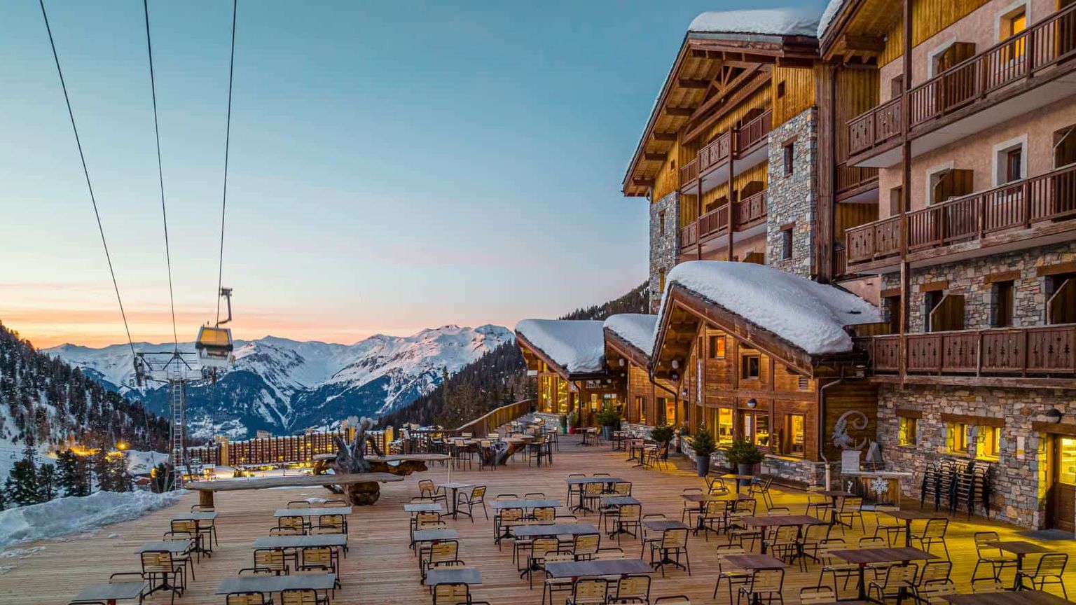een groot gebouw met veel tafels en stoelen ervoor, Hôtel Le Carlina door Les Etincelles, Les Arcs