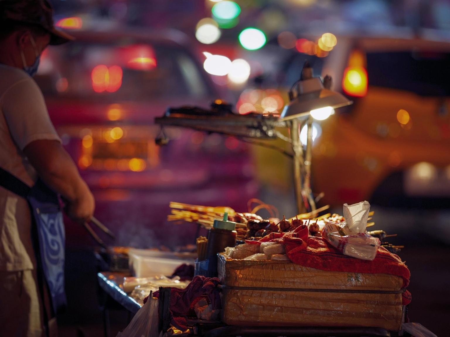Gadesælger, der griller madspyd på en vogn om natten. Bangkok
