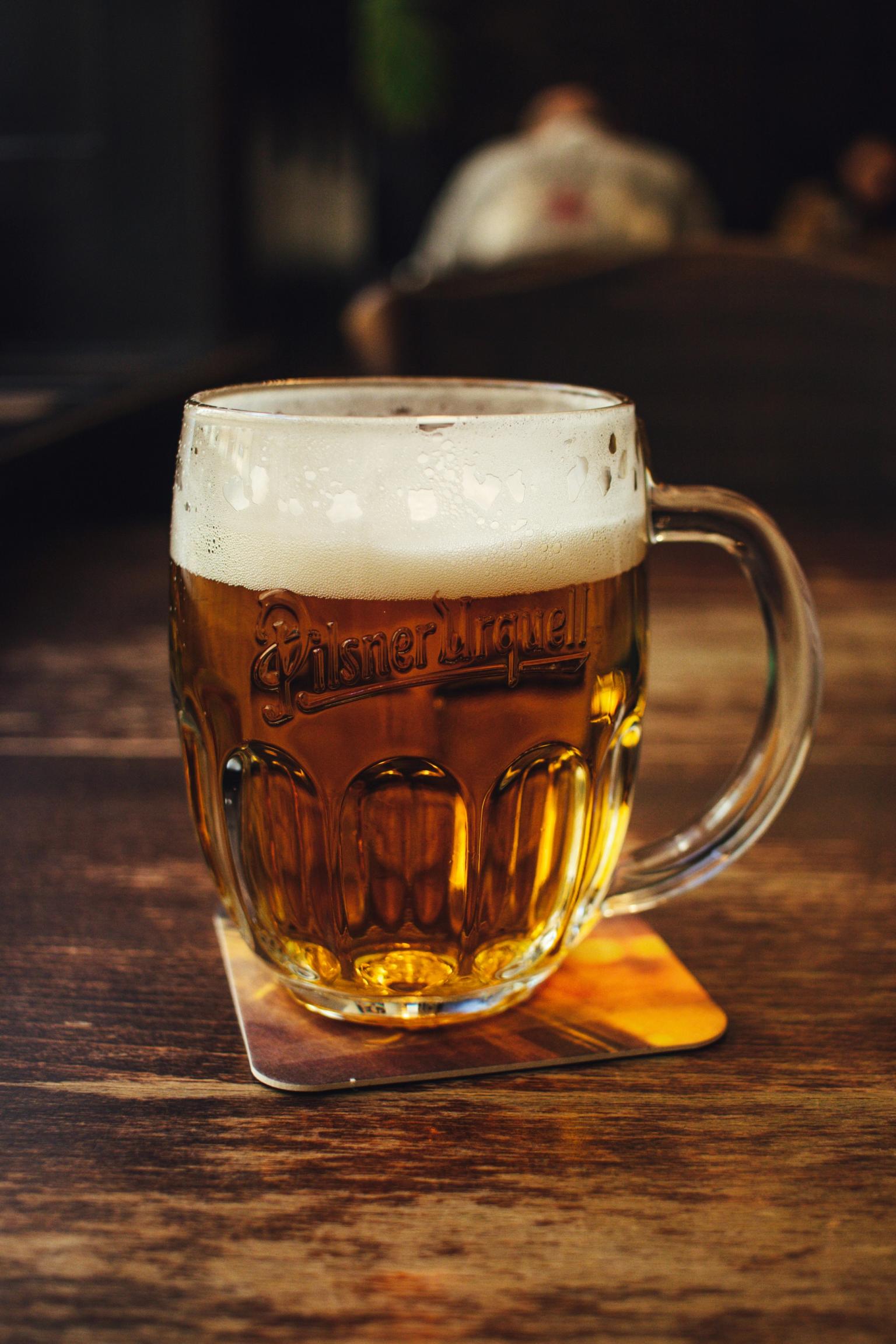 ett glas pilsner urquell öl på en underlägg