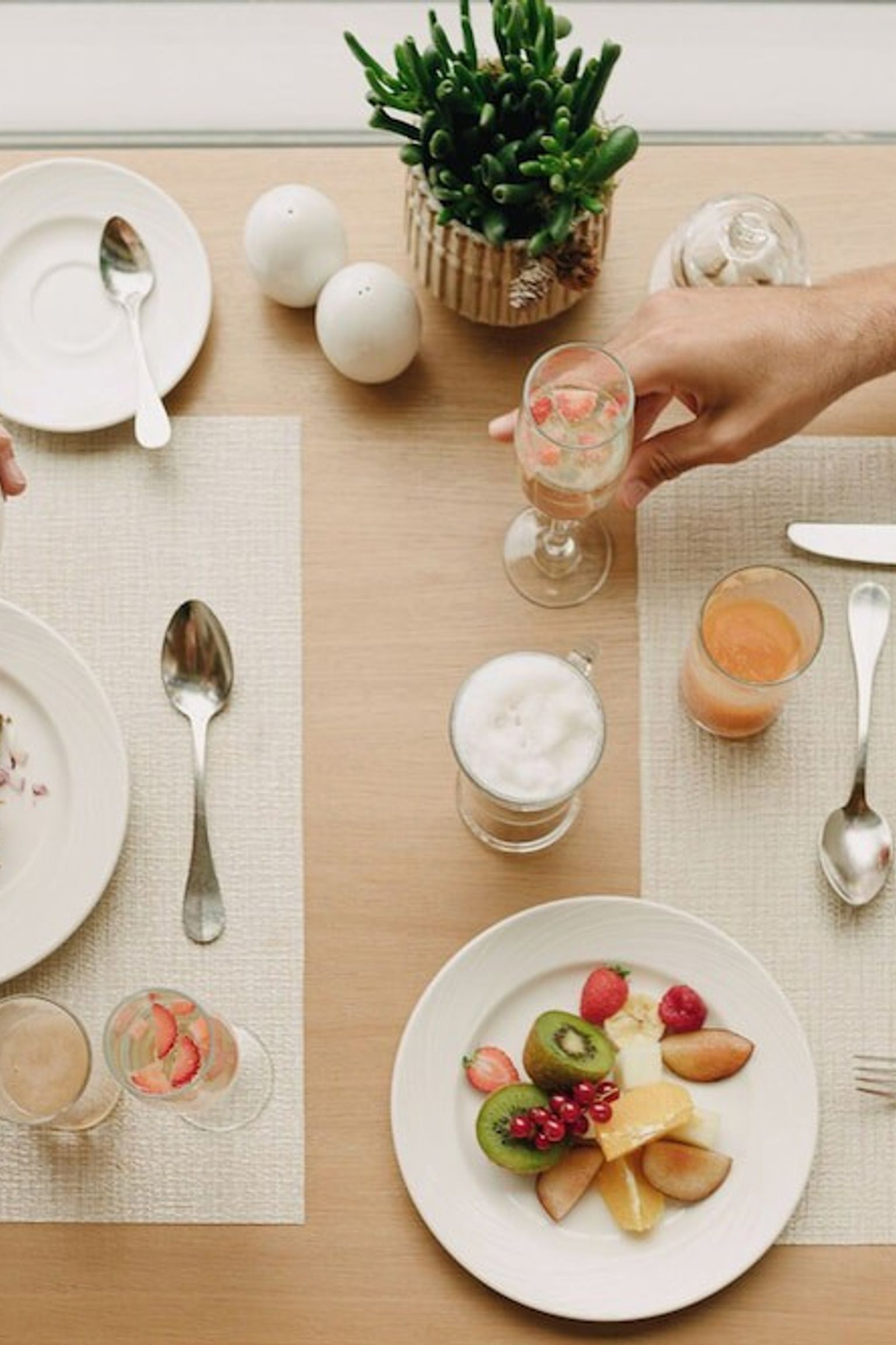 Draufsicht auf zwei Personen, die ein Frühstücksbuffet mit Kaffee, Obst und verschiedenen Gerichten genießen. Iberostar Selection Llaut Palma – Nur für Erwachsene