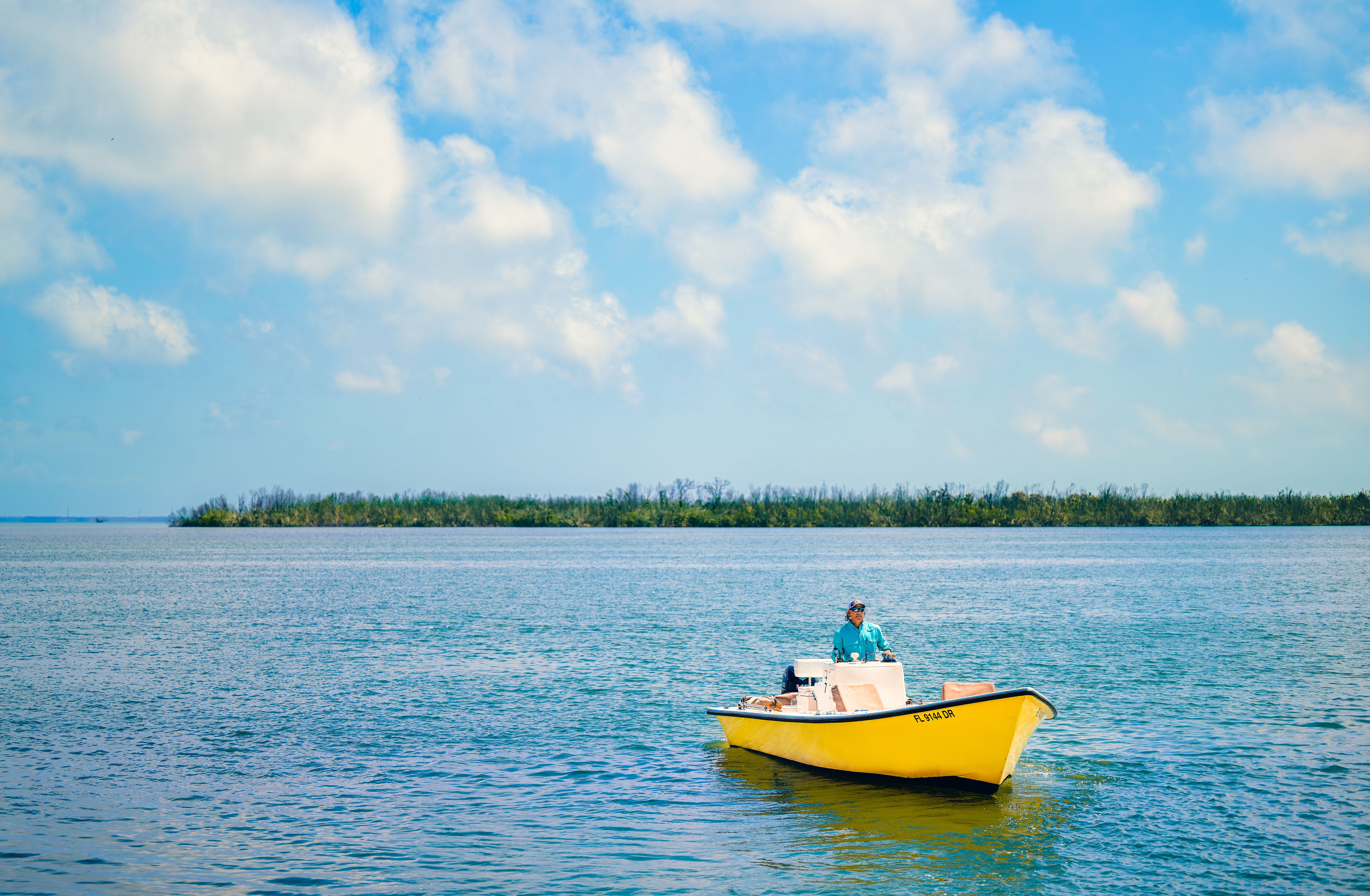 en mand i en gul båd flyder på toppen af en stor vandmasse.