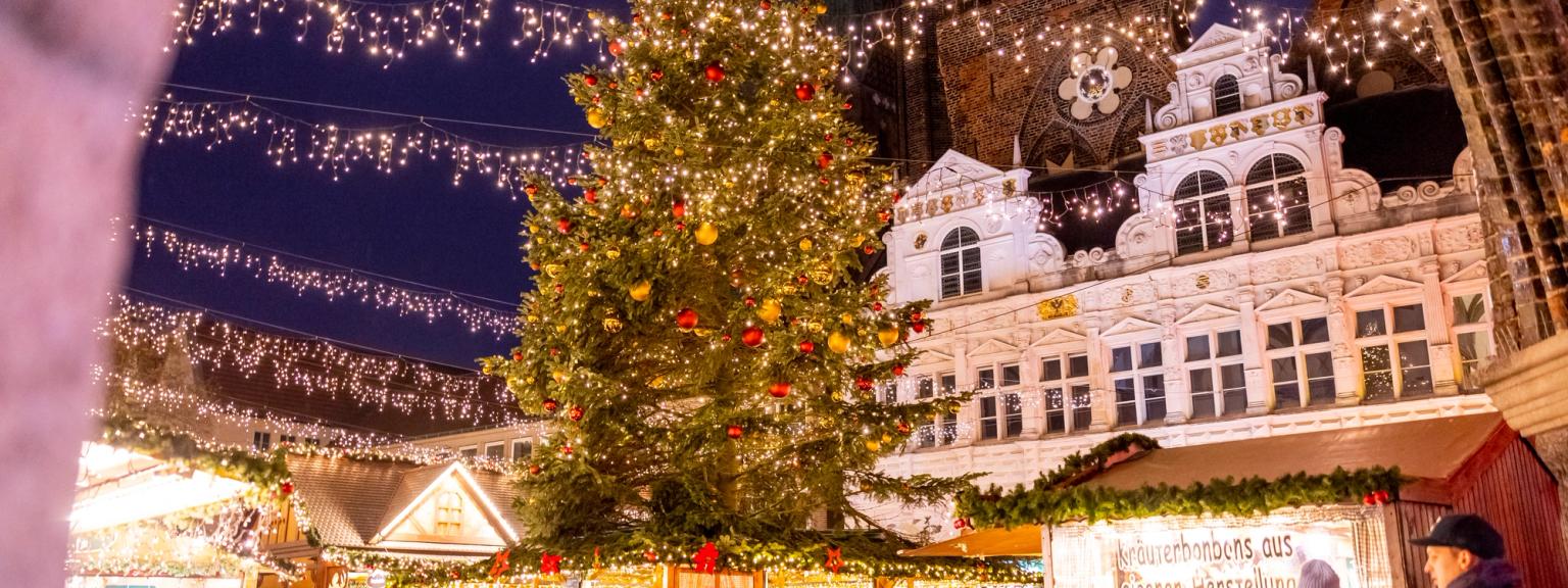 en grupp människor går runt en julmarknad med ett julgran i bakgrunden