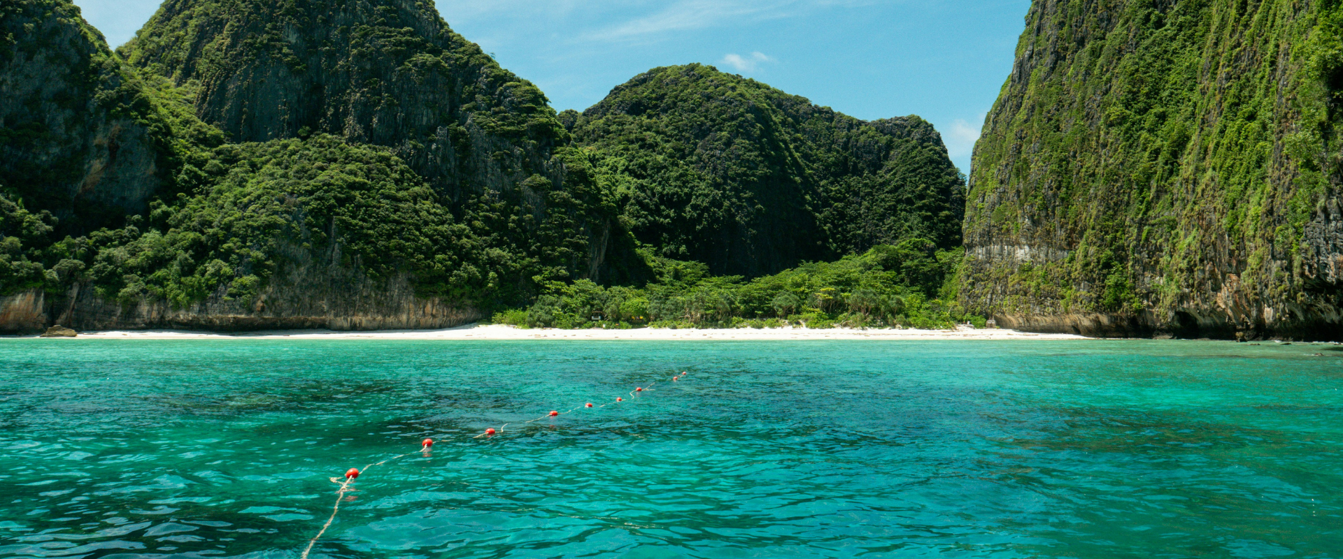 Strand og hav med bjerge i baggrunden
