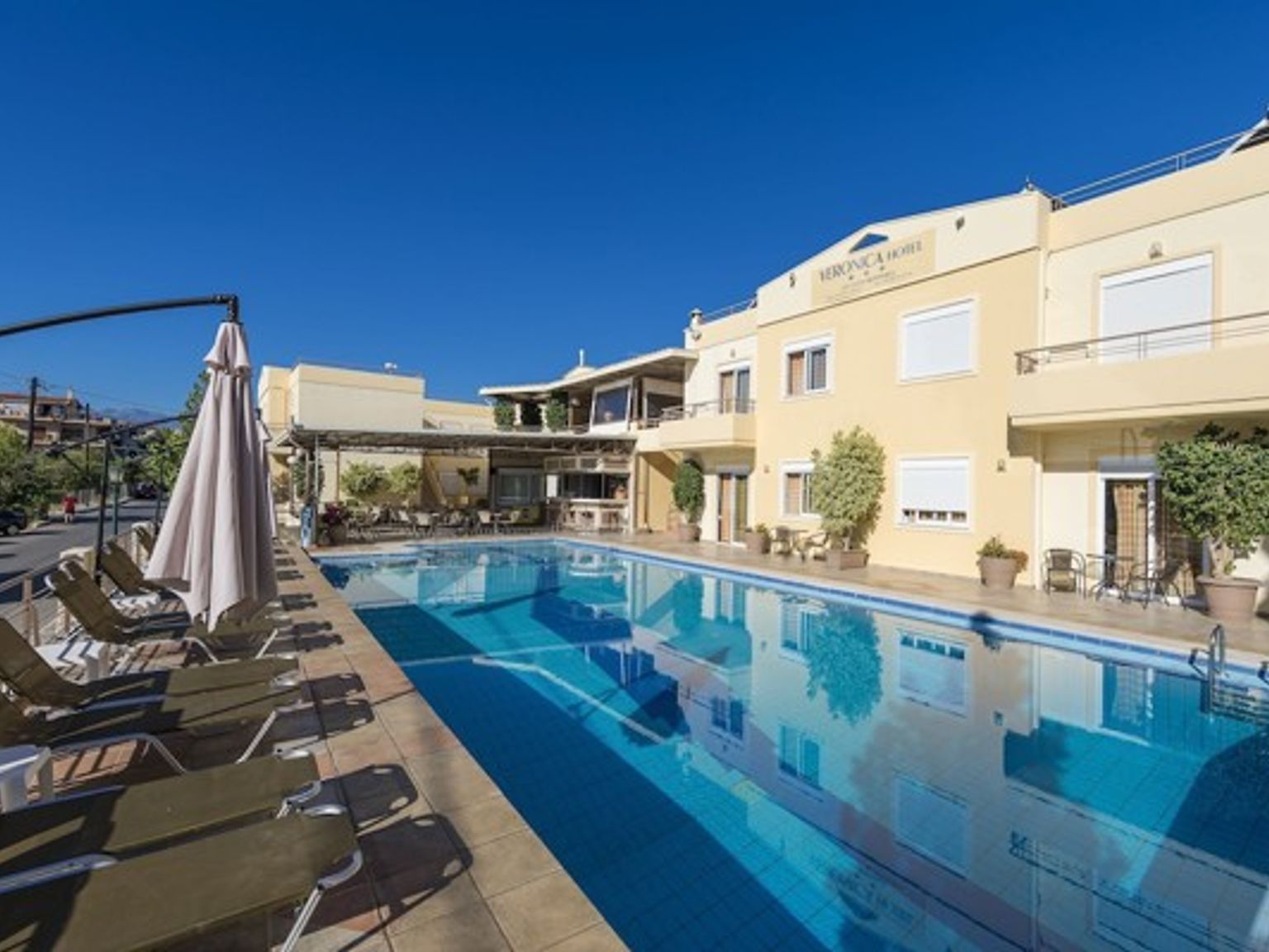 en stor simbassÀng omgiven av stolar och paraplyer framför ett hotell