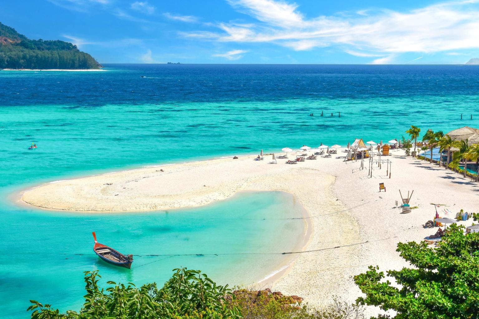 ein Boot schwimmt auf einer kleinen Insel mitten an einem tropischen Strand