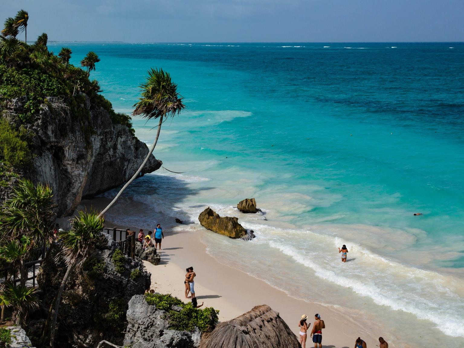 en gruppe mennesker står på en strand nær havet