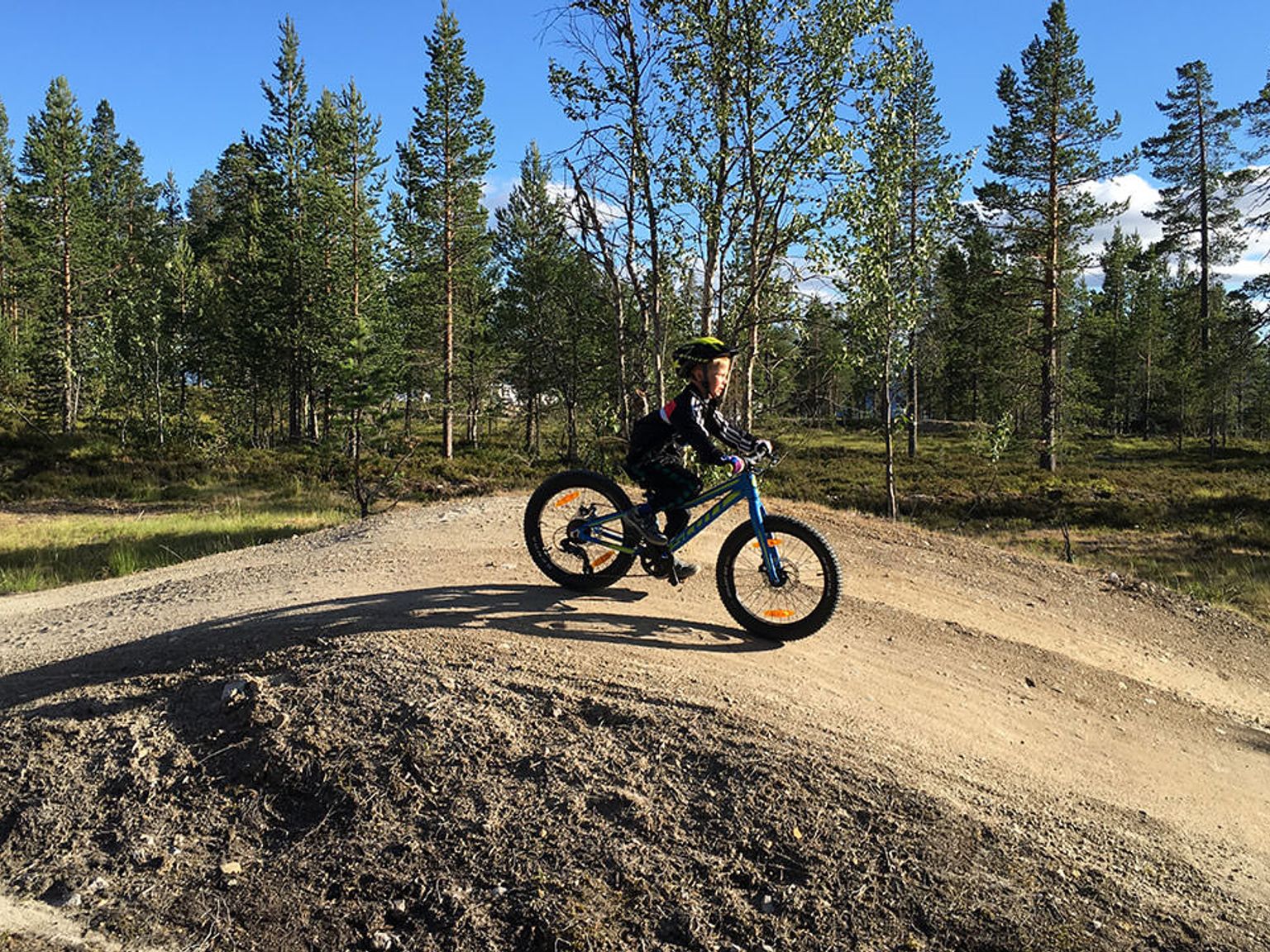 en ung dreng cykler på en grusvej