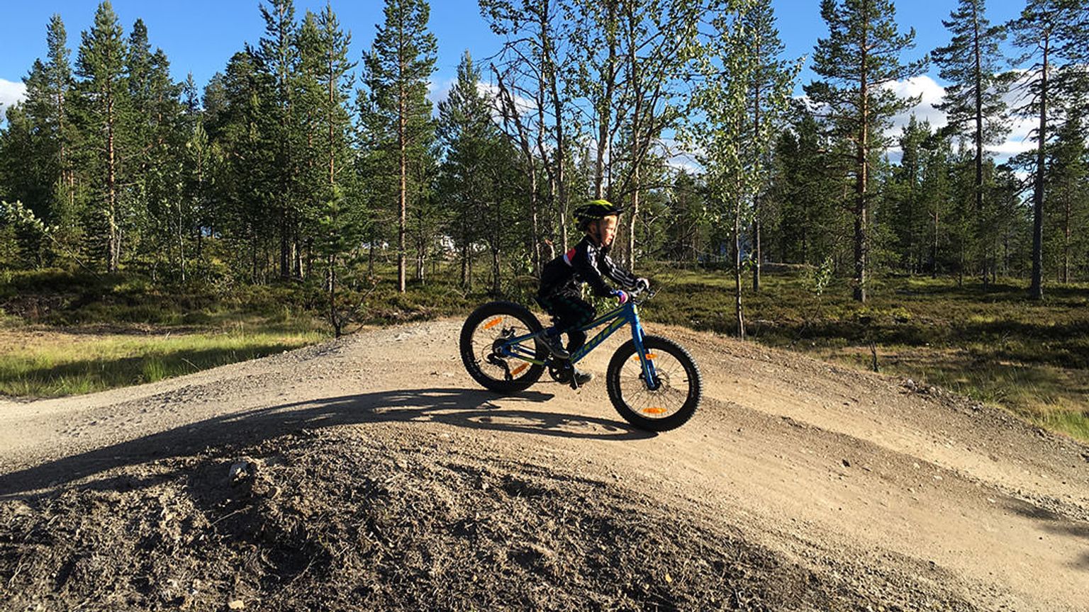 en ung gutt sykler på en grusvei
