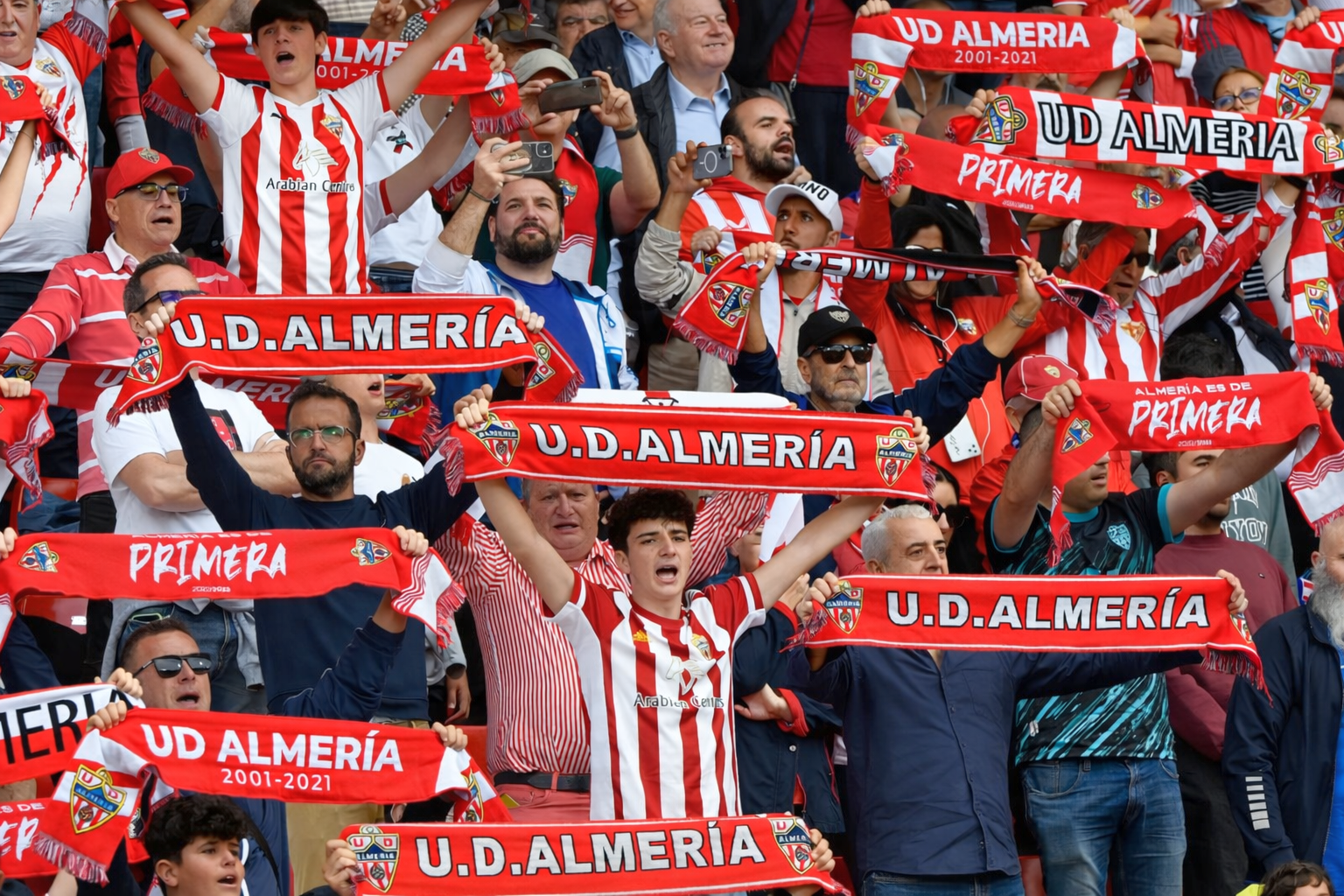 Fans von U.D. Almería, die jubeln und rot-weiße Schals hochhalten.