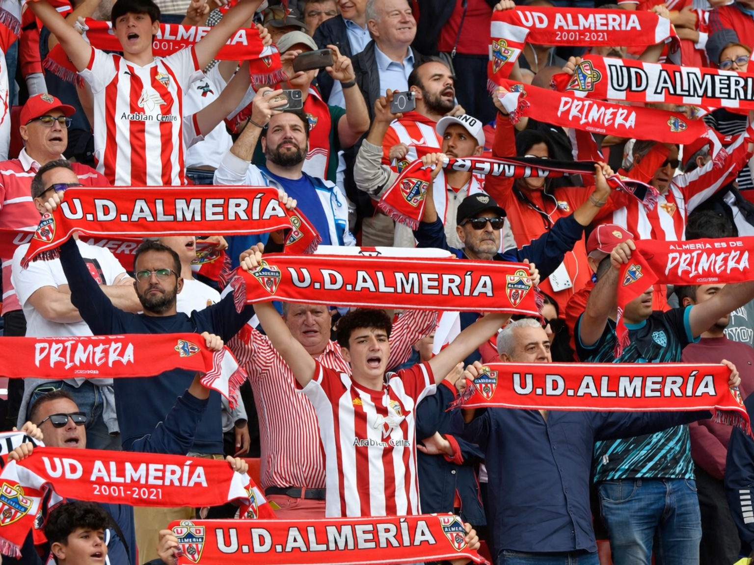 Fans von U.D. Almería, die jubeln und rot-weiße Schals hochhalten.