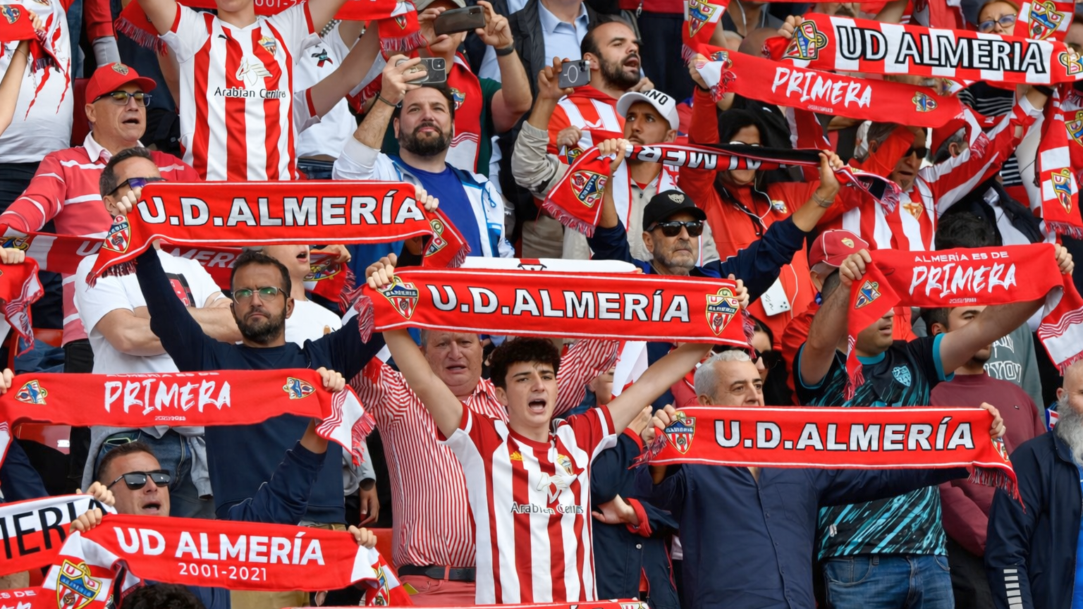 Fans till U.D. Almería som hejar och håller upp rödvita halsdukar.