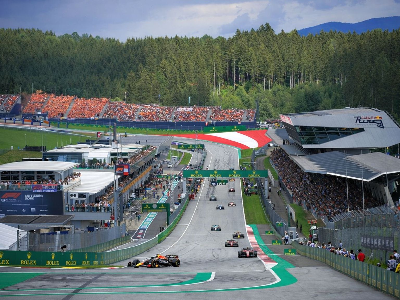 Formula 1 race at the Red Bull Ring with cars on track and spectators in the grandstands.