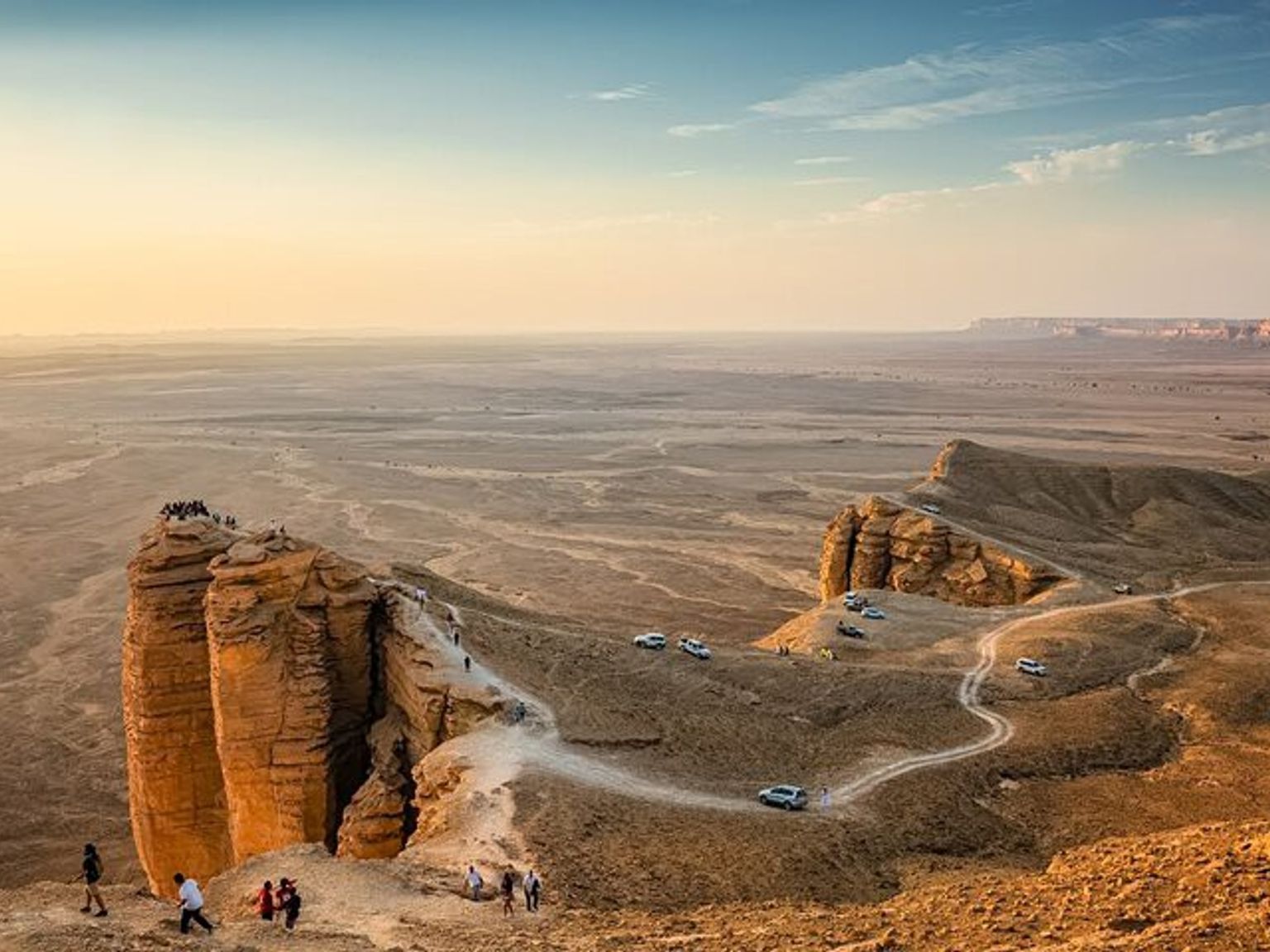 a group of people are standing on top of a desert cliff