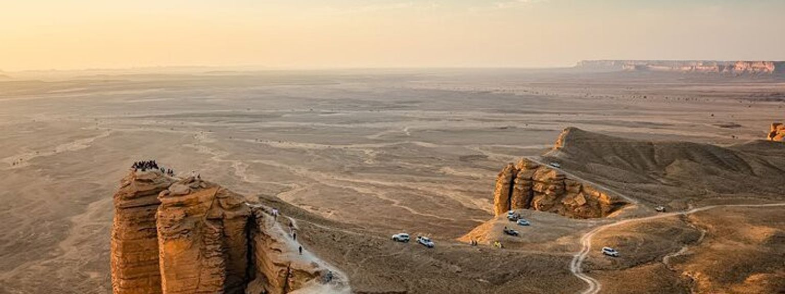 a group of people are standing on top of a desert cliff