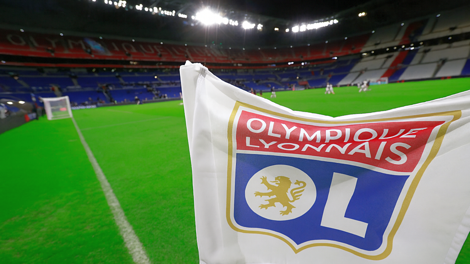 A close-up of an Olympique Lyonnais corner flag in a brightly lit soccer stadium.