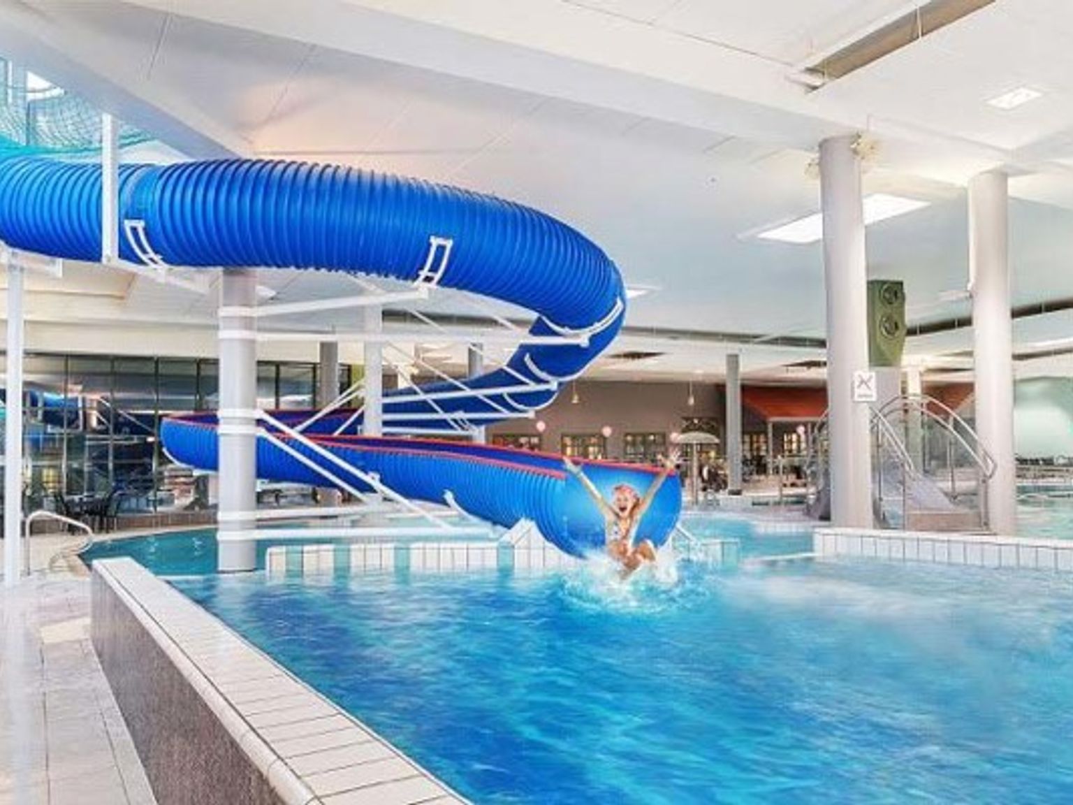 en person går ner en vattenrutschbana i en simbassäng