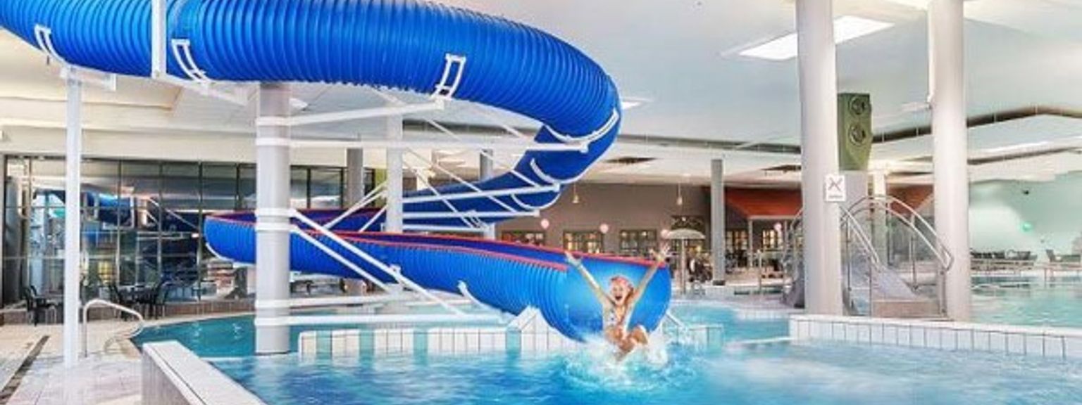 en person går ner en vattenrutschbana i en simbassäng