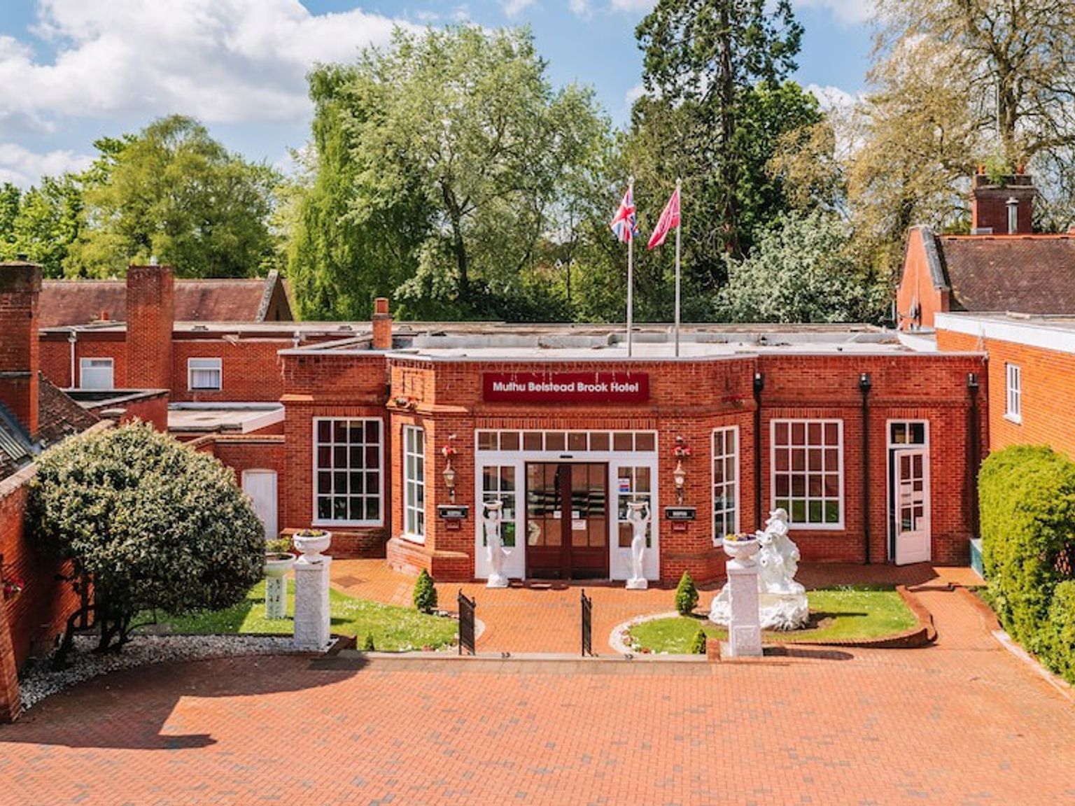 en stor rød murbygning med en murvei som fører til den