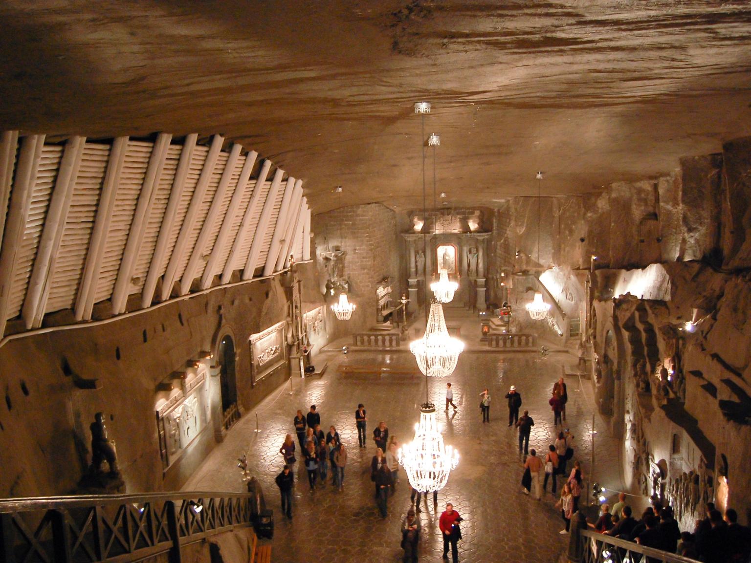 ett stort rum fyllt med människor och ljuskronor i en grotta
