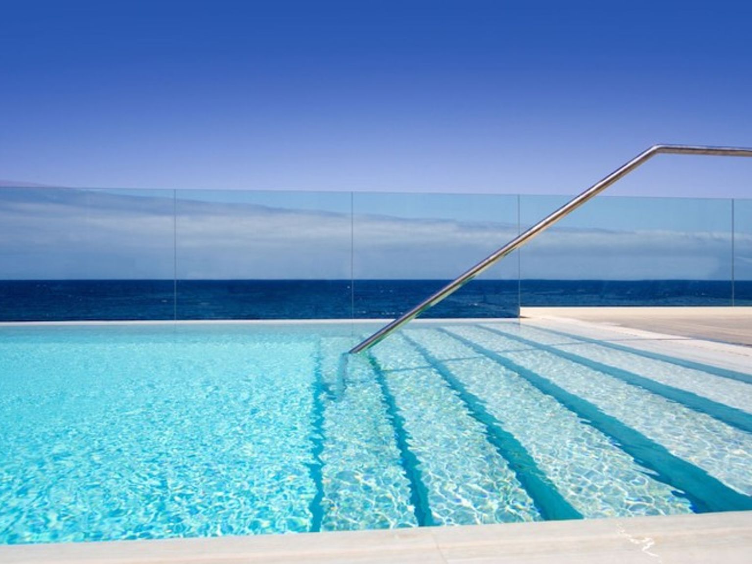 det er et svømmebasseng med trapper som fører til havet.