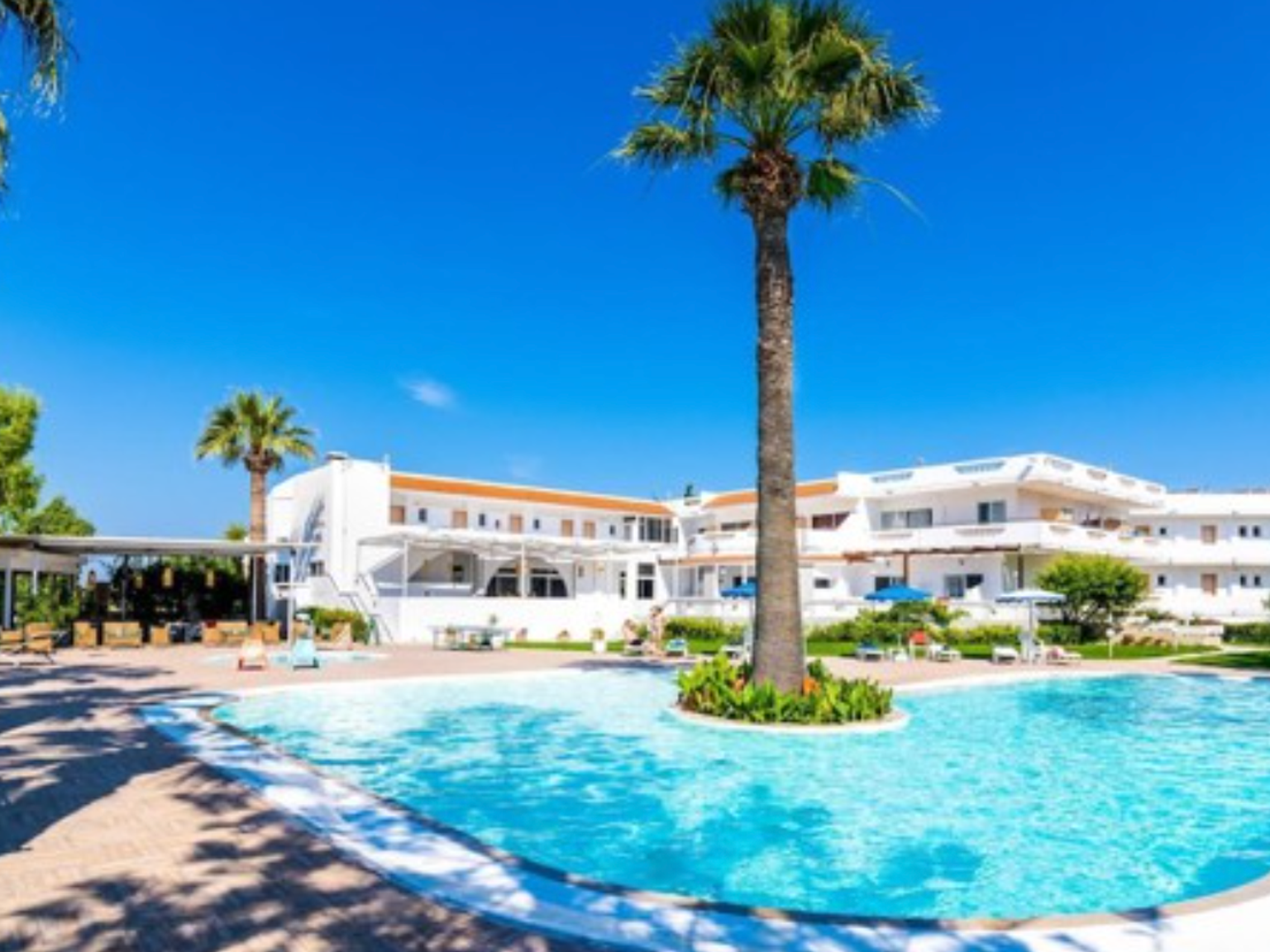 en stor simbassÀng omgiven av palmtrÀd framför ett hotell