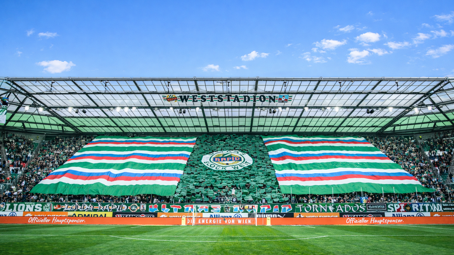 El estadio de fútbol Weststadion con aficionados mostrando una gran pancarta verde, blanca y roja a través de las gradas.