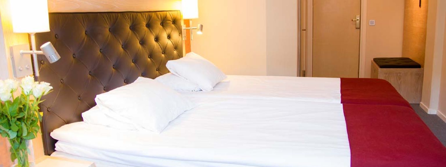 et hotelværelse med to senge og en vase med blomster på natbordet