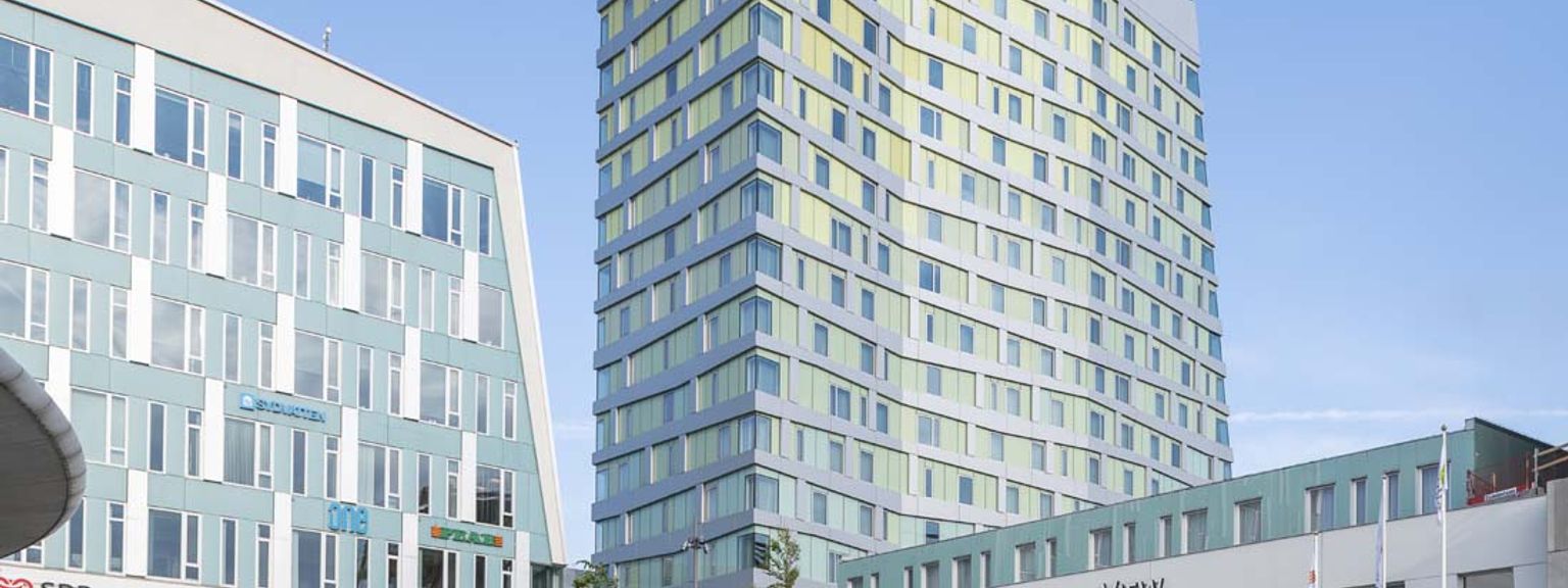 a tall building with a lot of windows is sitting next to a smaller building