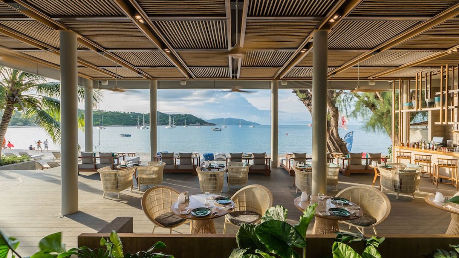 en restaurang med bord och stolar med utsikt över havet