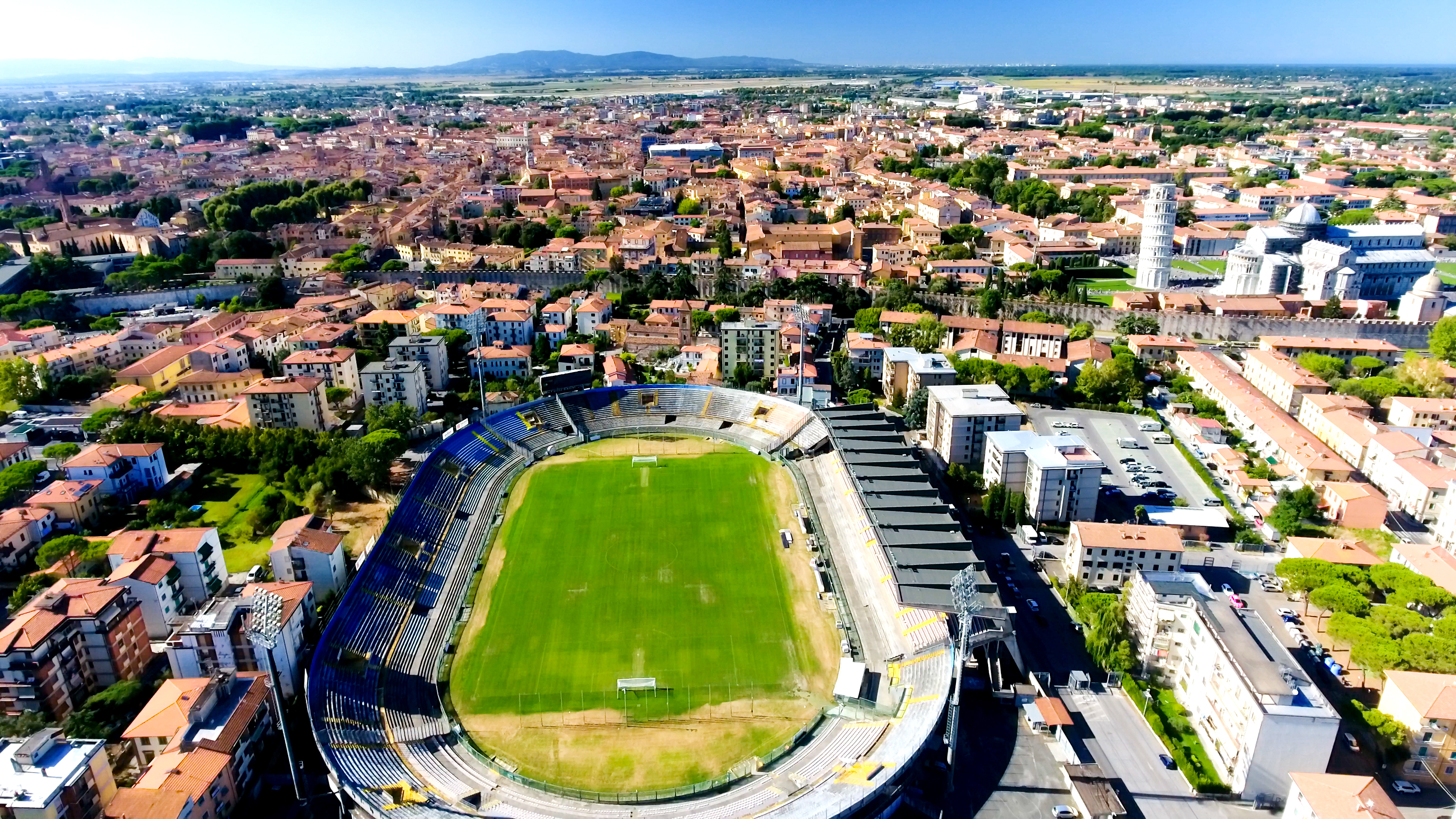 Aerial view of a city featuring a stadium and the Leaning Tower of Pisa.